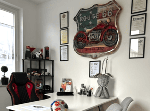 Modernes Büro mit Route 66-Schild, Rennstuhl in Schwarz-Rot, Dokumenten an den Wänden.